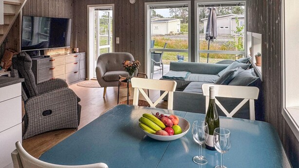 A dining area with a table set for two, a bowl of fruit, and a bottle of wine. - 4 bedroom awesome home in Færvik (Færvik)
