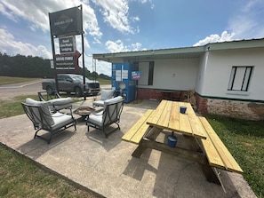 A drive-thru area with a sign for the Sahara Club, outdoor seating, and a water dispenser.
