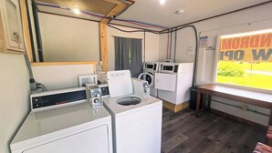 A laundry room with a Speed Queen commercial dryer, a front-loading washer, and a wall-mounted washing machine. - Motel Room 4 with Bar & Grill and Laundromat (Copperhill)