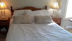 A neatly made bed with white linens and two decorative pillows, flanked by two bedside tables with lamps. - Creativity Spa Studio, be inspired, rejuvenated & relaxed, Heaven on Earth! (Bracebridge)