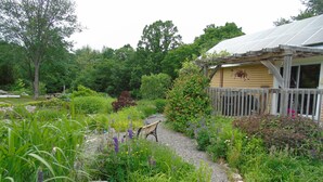 A garden with a wooden bench, a rock, and a house with a wooden fence. - Creativity Spa Studio, be inspired, rejuvenated & relaxed, Heaven on Earth! (Bracebridge)