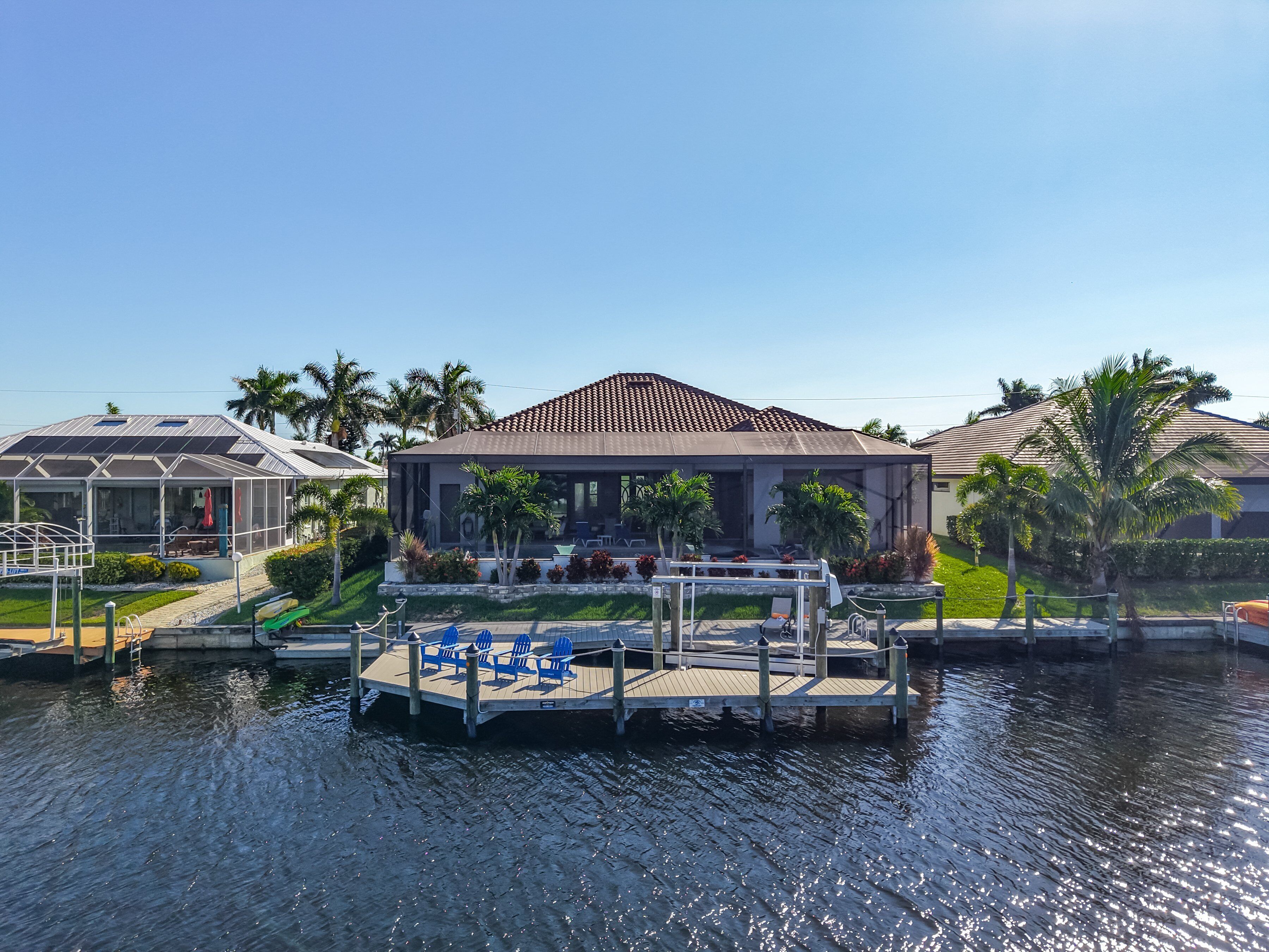 A waterfront property with a dock, a covered patio, and a pool area.