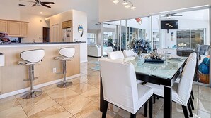 Cozinha moderna com área de bar, mesa de jantar e cadeiras, e uma janela grande que oferece vista para o exterior.
