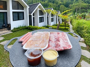 Ein Tisch mit rohem Fleisch, Soßen und einem Haus im Hintergrund.
