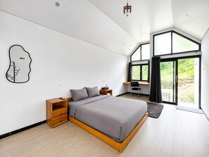 Een moderne slaapkamer met een bed, houten nachtkastjes, een bureau en een groot raam.
