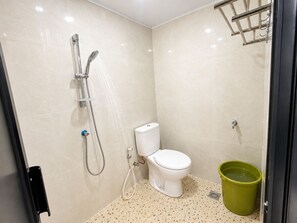 Een kleine, privé badkamer met toilet, douche en een groene emmer.