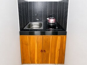 Eine Küche mit schwarzer Arbeitsplatte, Spüle aus Edelstahl und einem rosa Wasserkocher.