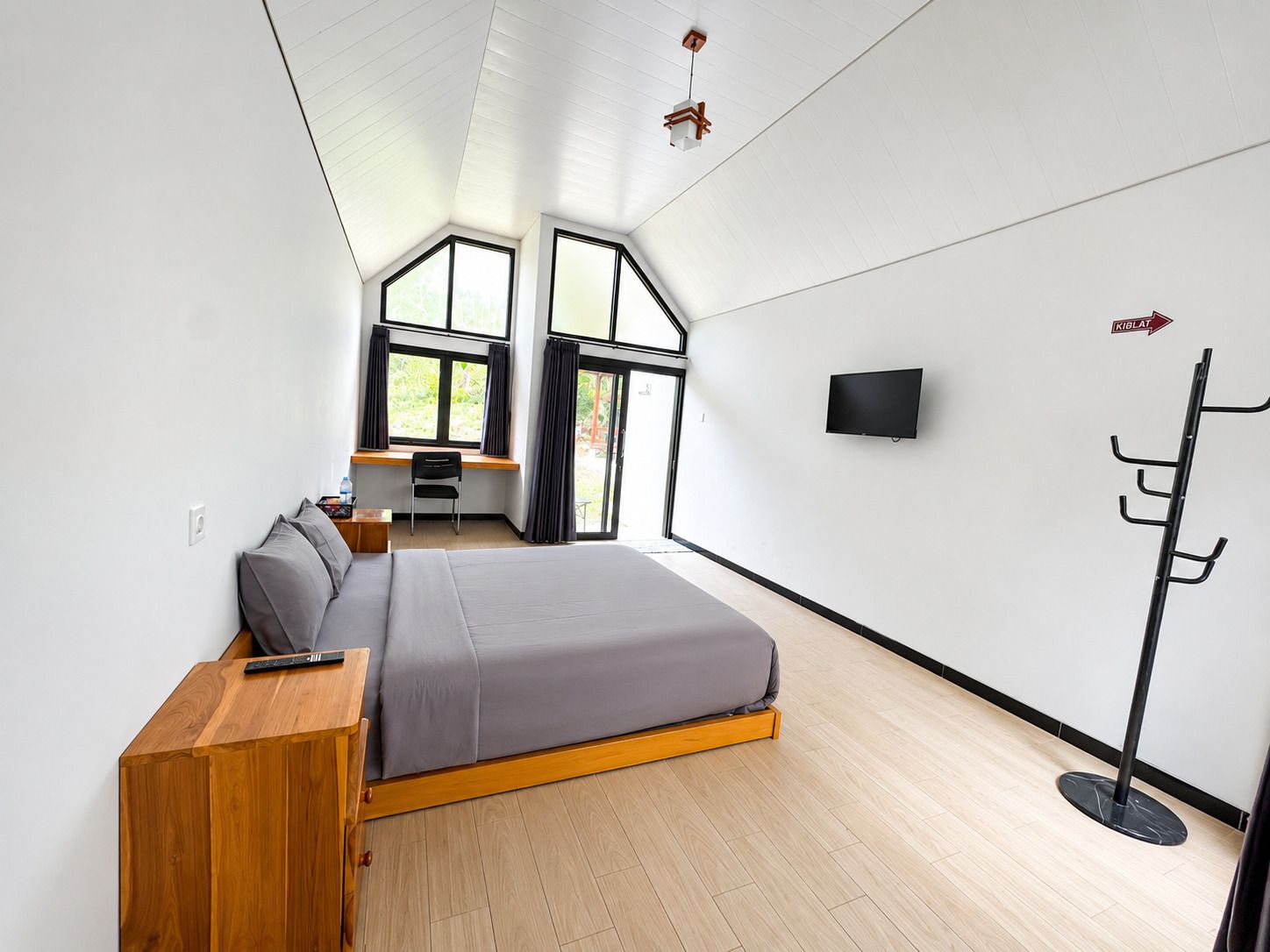 A modern bedroom with a bed, a desk, and a TV.