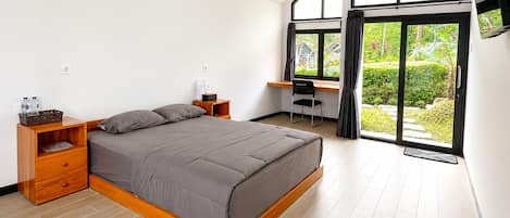 Une chambre à coucher moderne, avec un lit, des tables de chevet en bois, un bureau et une grande fenêtre donnant sur un paysage verdoyant.