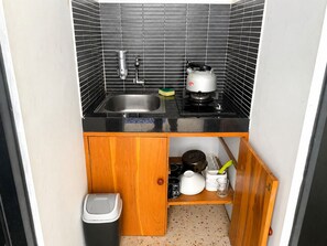 Eine kleine Küche mit Spüle, Herd und einem Schrank darunter.