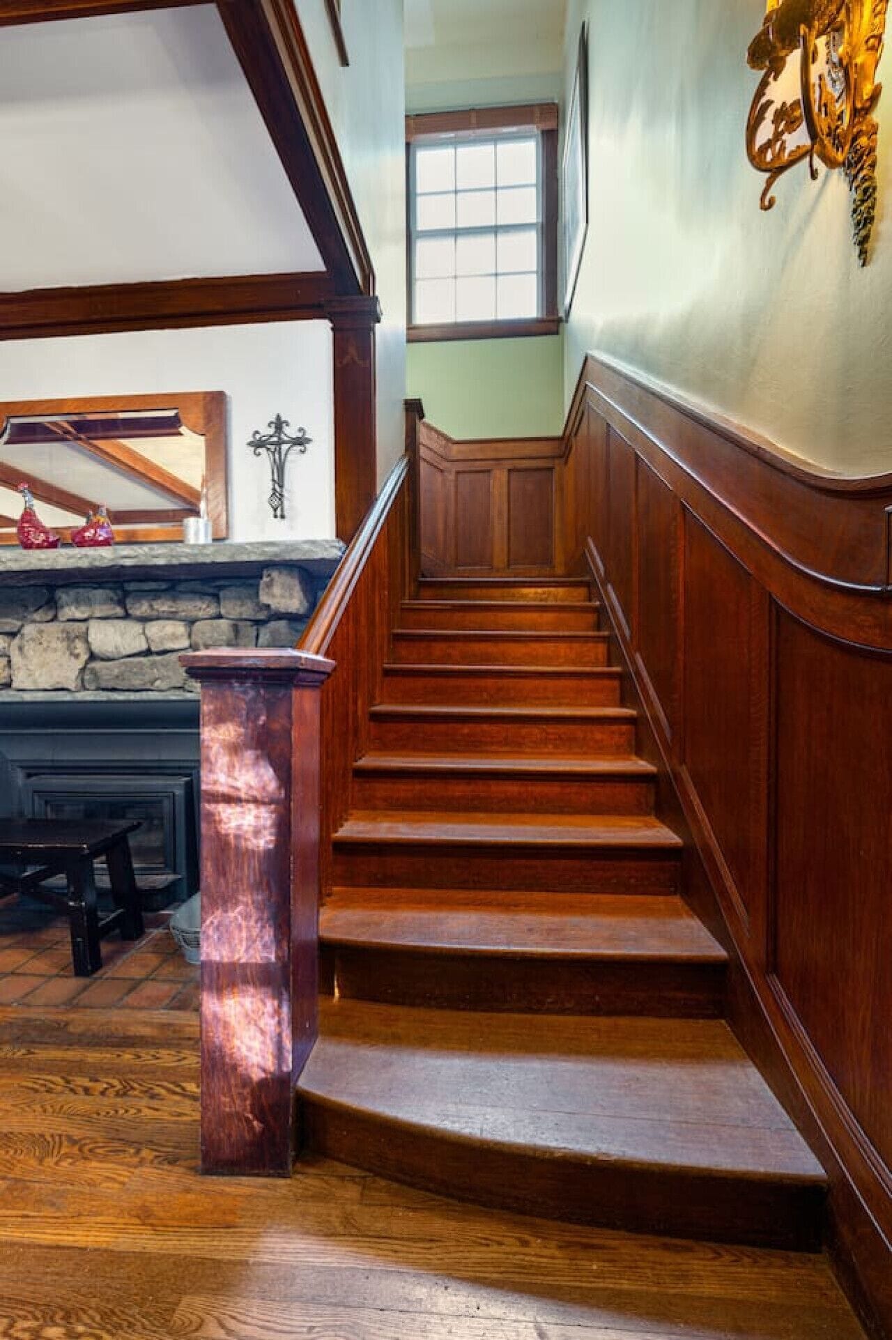 A wooden staircase with a stone wall and a window above.