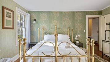 A room with a bed, a window, a door, and a wall with a patterned wallpaper.
