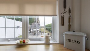 Una cucina con una finestra, un contenitore per il pane bianco e un piatto con delle mele.