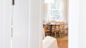 Un'area pranzo con tavolo e sedie, una finestra con tende e un orologio appeso al muro.