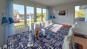 Ein Essbereich mit einem Tisch für vier Personen, weißen Stühlen und einer Tischdecke mit Muster.