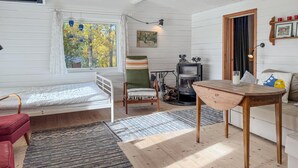 A cozy room with a bed, a chair, a table, a fireplace, and a window with a view of trees. - Gorgeous home in Rörvik with WiFi (Rörvik)
