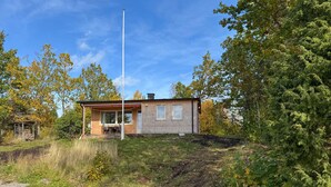 A small wooden cabin with a single window, a chimney, and a porch with a chair. - Gorgeous home in Rörvik with WiFi (Rörvik)