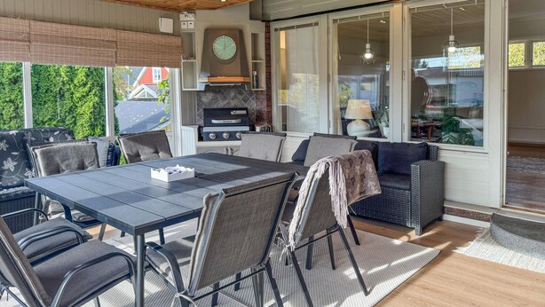 Un área de patio techada con una mesa de comedor, sillas y un sofá.