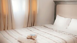 Una cama bien hecha con ropa de cama a rayas, un cabecero de madera y un par de toallas dobladas sobre la cama.