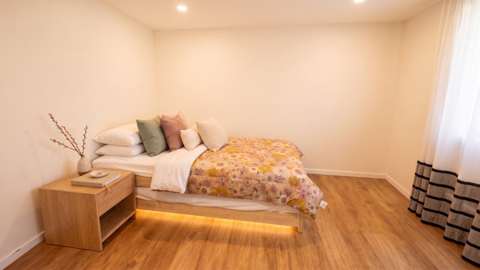 A bedroom with a bed, bedside table, and a nightstand.