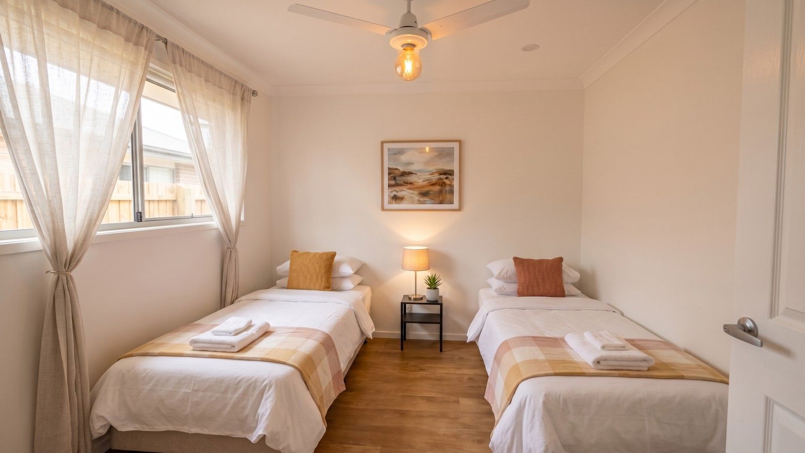Una habitación de hotel con dos camas, una mesita de noche con lámpara y un cuadro en la pared.