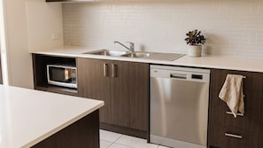 A modern kitchen with a built-in microwave, a stainless steel dishwasher, and a sink with a faucet.