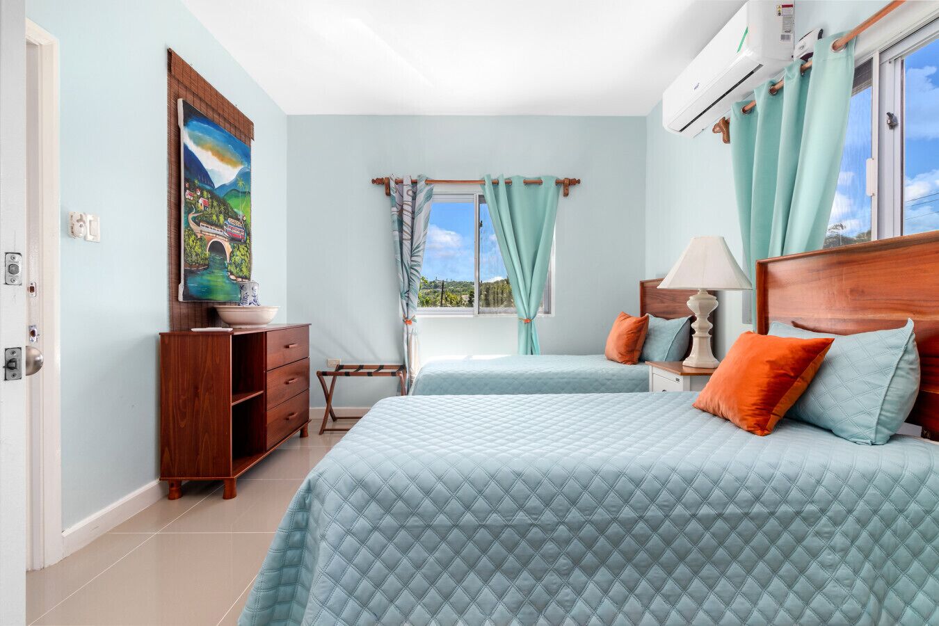 A bedroom with two beds, a wooden dresser, a painting on the wall, and a window with curtains.