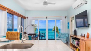 A kitchen with a large island, a dining area with a view of the ocean, and a TV mounted on the wall. - Teal Horizon Oceanfrontcaribbean Escape Tower Isle (Tower Isle)