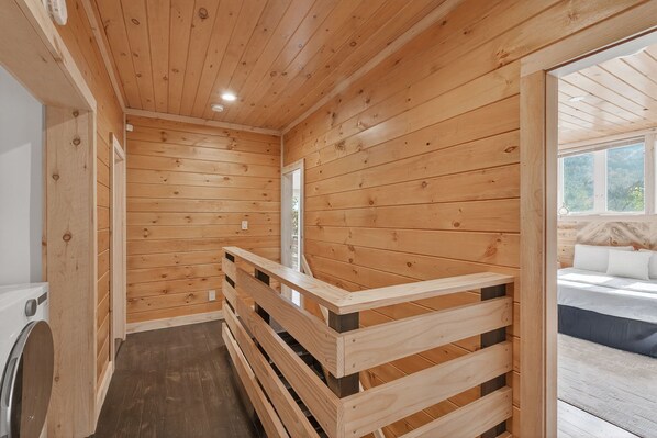A wooden interior with a wooden staircase leading to a balcony.