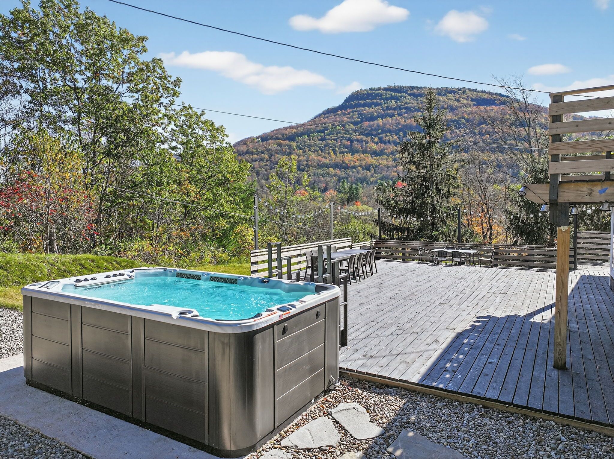 Een hottub op een houten terras met uitzicht op de bergen.