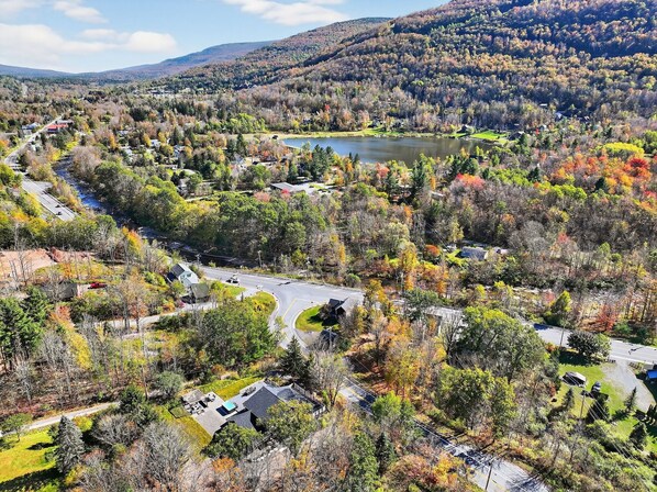 A residential area with a winding road, houses, and a lake surrounded by trees. - Luxury 7BR Ski Retreat Near Hunter & Windham w/ Hot Tub & Epic Mountain Views (Hunter)