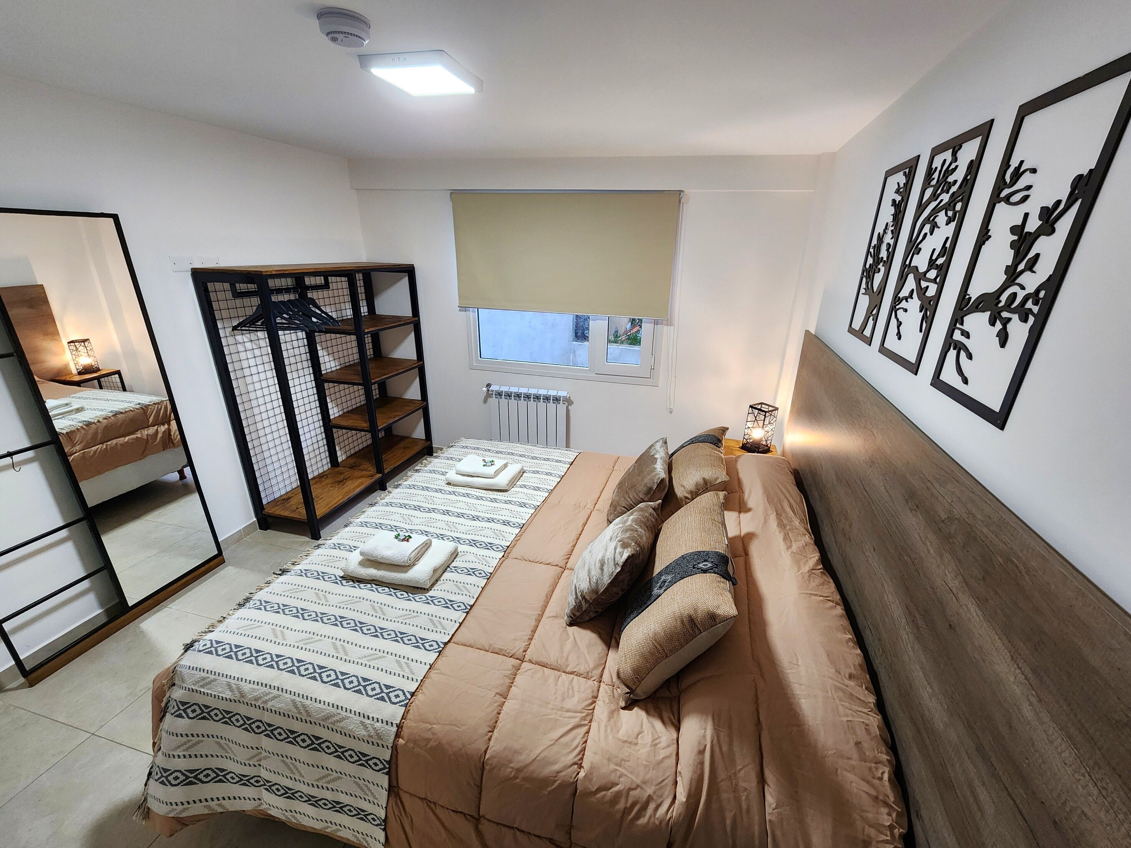 A bedroom with a bed, a wardrobe, a window with a view, and wall art.