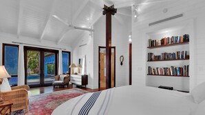 A spacious bedroom with a large bed, a bookshelf, and a view of a swimming pool.