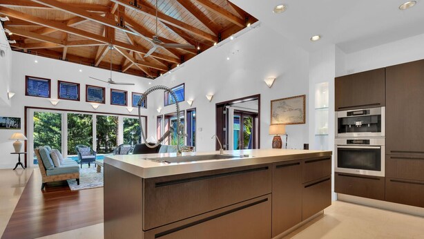 A modern kitchen with a large island, built-in appliances, and a view of the outdoors.