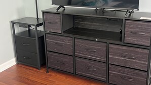 A modern entertainment unit with a flat-screen TV, multiple drawers, and a lamp.