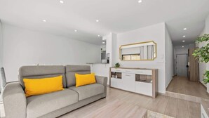 A modern living room with a grey sofa, yellow cushions, a white coffee table, and a wooden cabinet with a mirror above it.