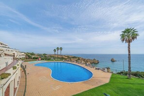Un resort con una gran piscina, vistas al mar y una palmera.