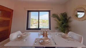 Zona pranzo con tavolo apparecchiato per quattro, una finestra con vista su un resort e una pianta in vaso.