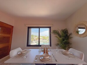 A dining area with a table set for four, a window with a view of a resort, and a potted plant.