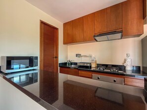 A modern kitchen with wooden cabinets, a stainless steel microwave, a coffee machine, and a sink.