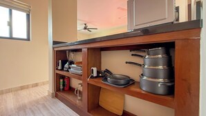 Una cucina con mensole in legno, un forno a microonde, una ventola a soffitto e diversi utensili da cucina.
