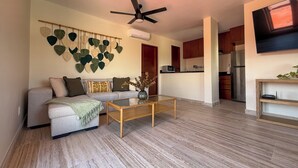 Una sala moderna con un sofá, una mesa de centro y una planta colgada en la pared.
