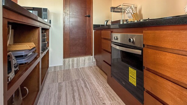 Una cucina compatta con mobili in legno, un forno a microonde e un fornello.