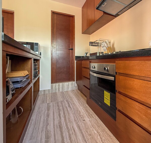 A compact kitchen with wooden cabinets, a microwave, and a stove.