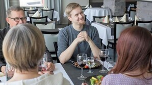 A group of people dining at a restaurant with a table set for a meal, glasses of wine, and a plate of food. - Inari Hotel (Inari)