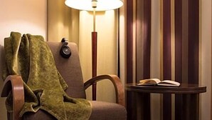 A room with a chair, a table, a lamp, and striped curtains. - Inari Hotel (Inari)