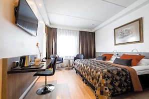 A hotel room with a bed, a desk with a chair, a TV mounted on the wall, and a painting on the wall. - Inari Hotel (Inari)