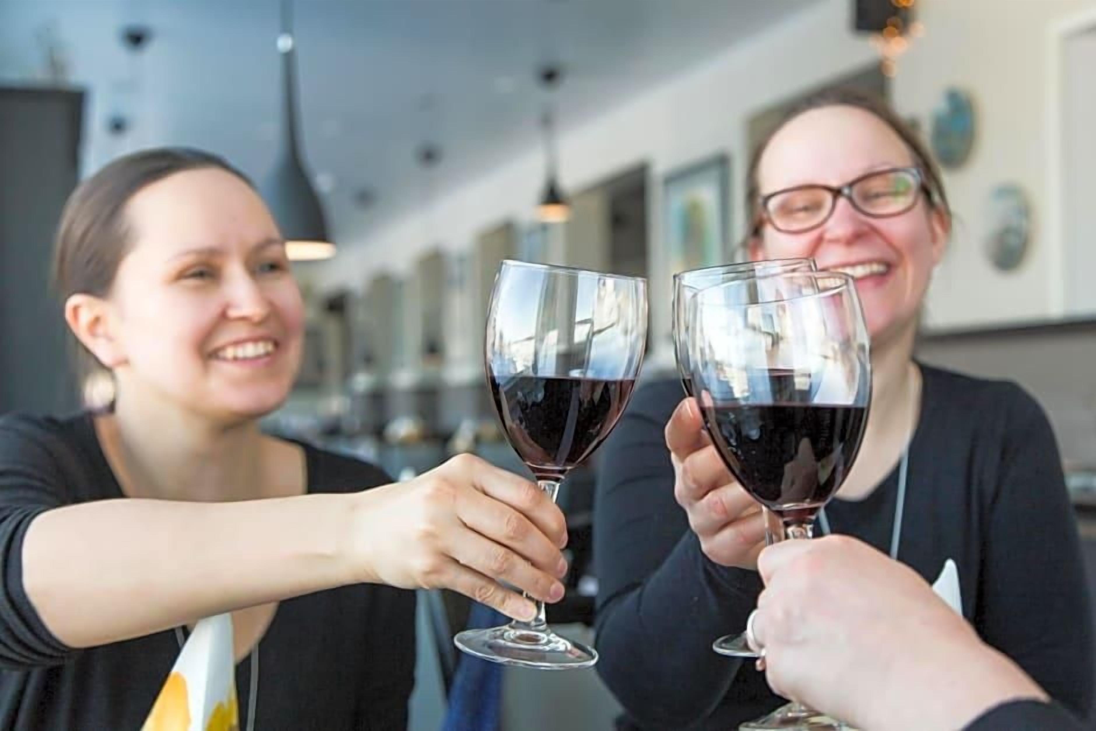 Kaksi ihmistä kohottaa viinilasejaan modernissa sisustetussa tilassa, jossa on riippuvalaisimet.