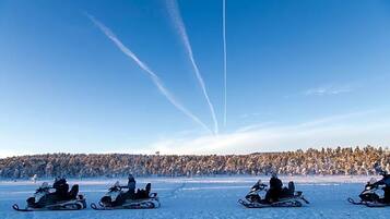 Un grupo de motos de nieve en un paisaje nevado con cielo despejado.