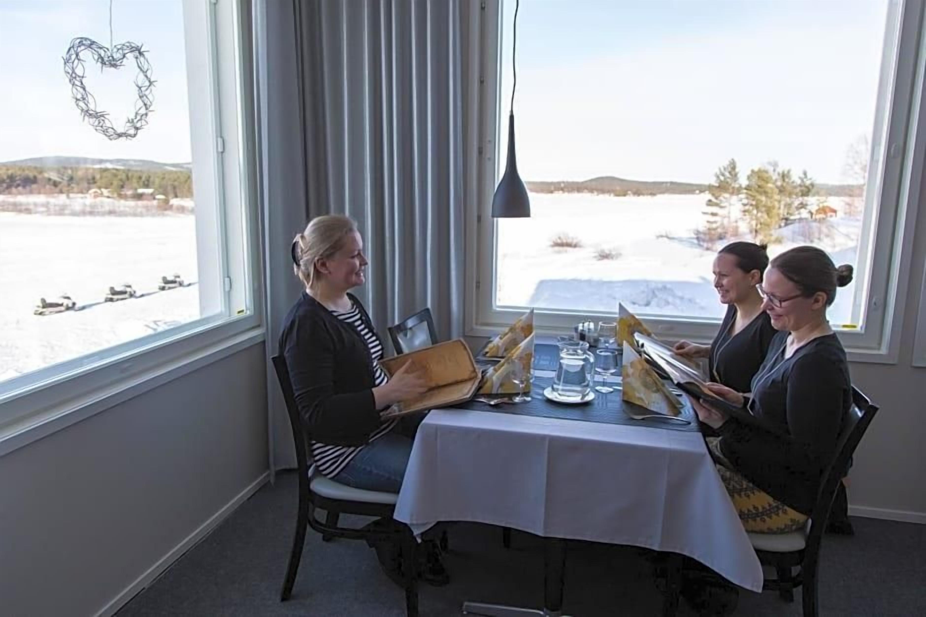 A dining table with a white tablecloth, chairs, and a view of a snowy landscape through a window.